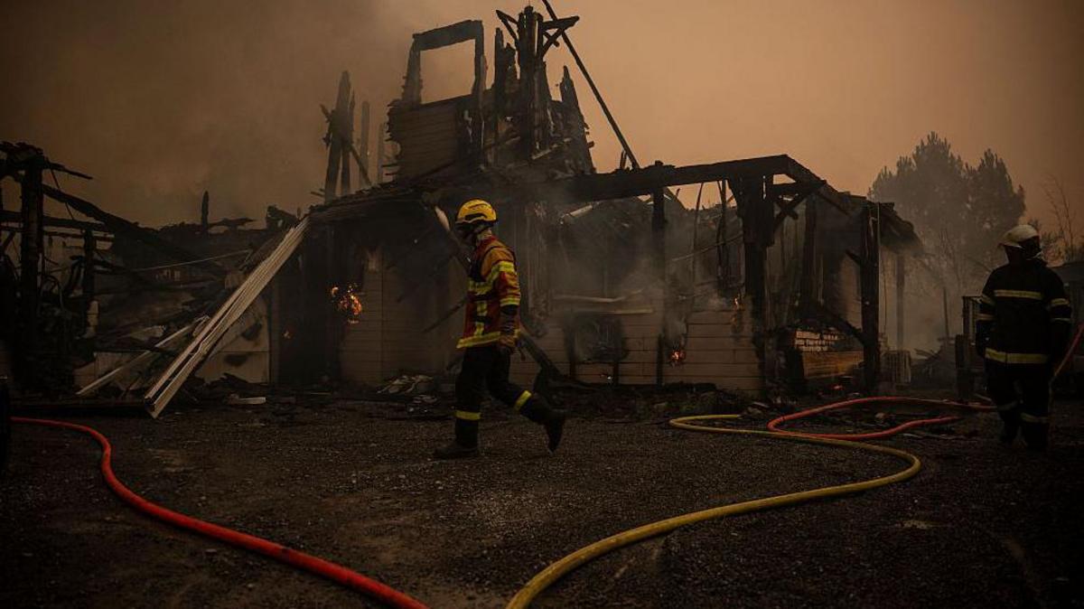 A firefighter walks in front of a burnt out building