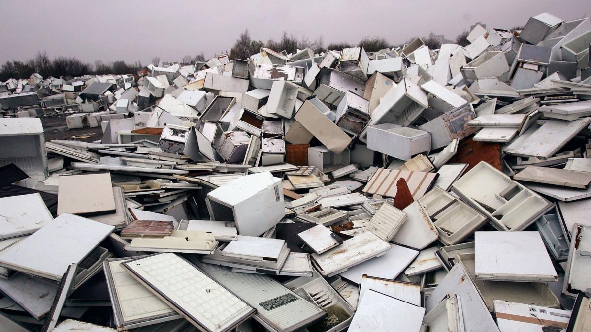 A huge pile of broken fridges is pictured, with white doors removed from some units.