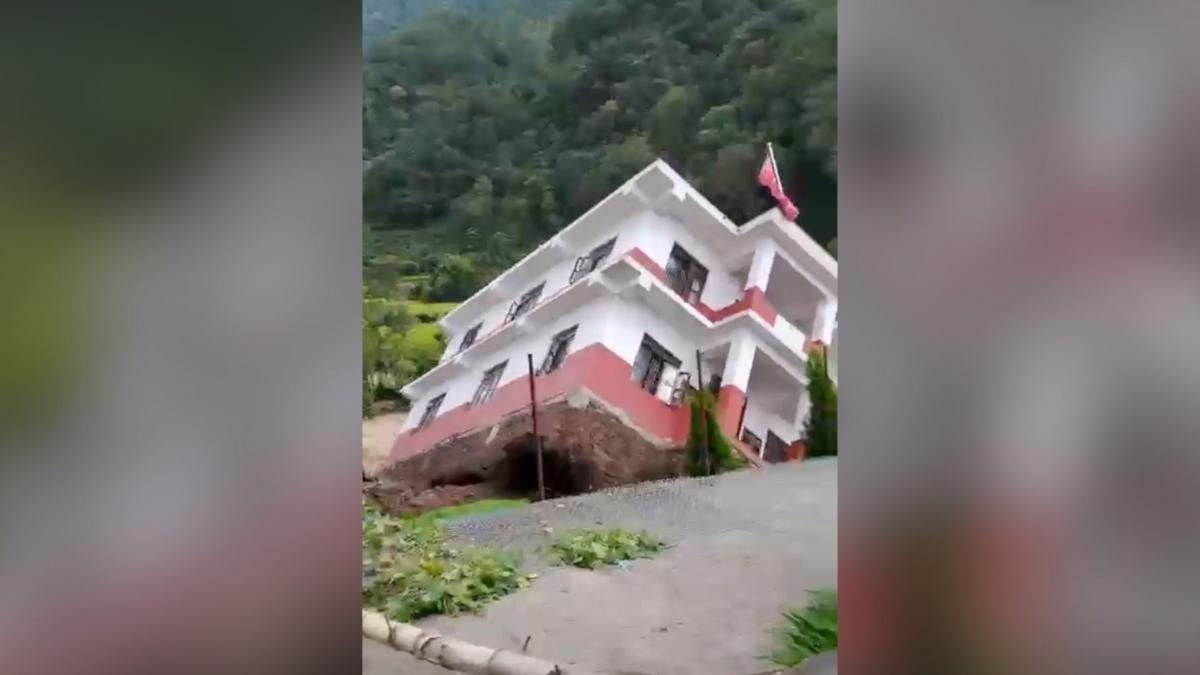 White building falling into a river