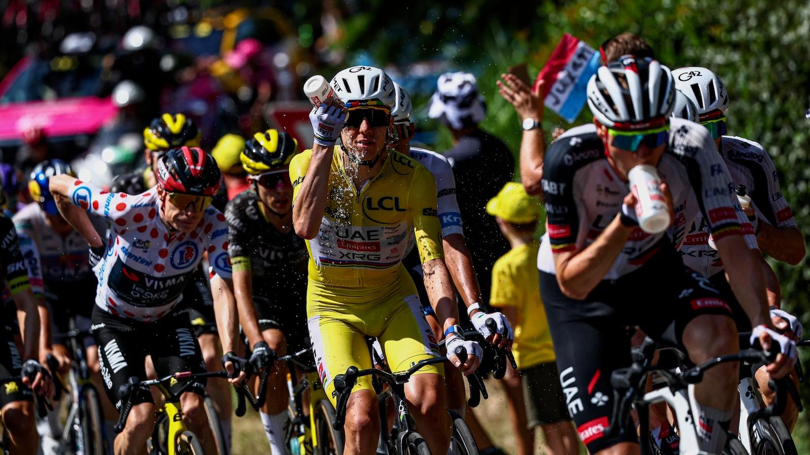A line of cyclists competing in the Tour de France douse themselves with water to stay cool.