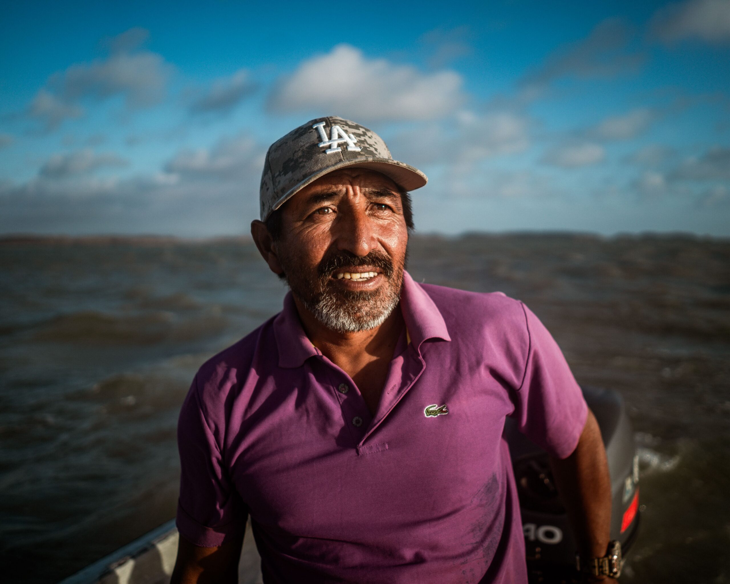 Wilfrido Arends, 46, an Indigenous Wayuu fisher known locally as “Caracas,” scans the horizon as he steers the onboard motor of his small fishing boat. Image by Euan Wallace.