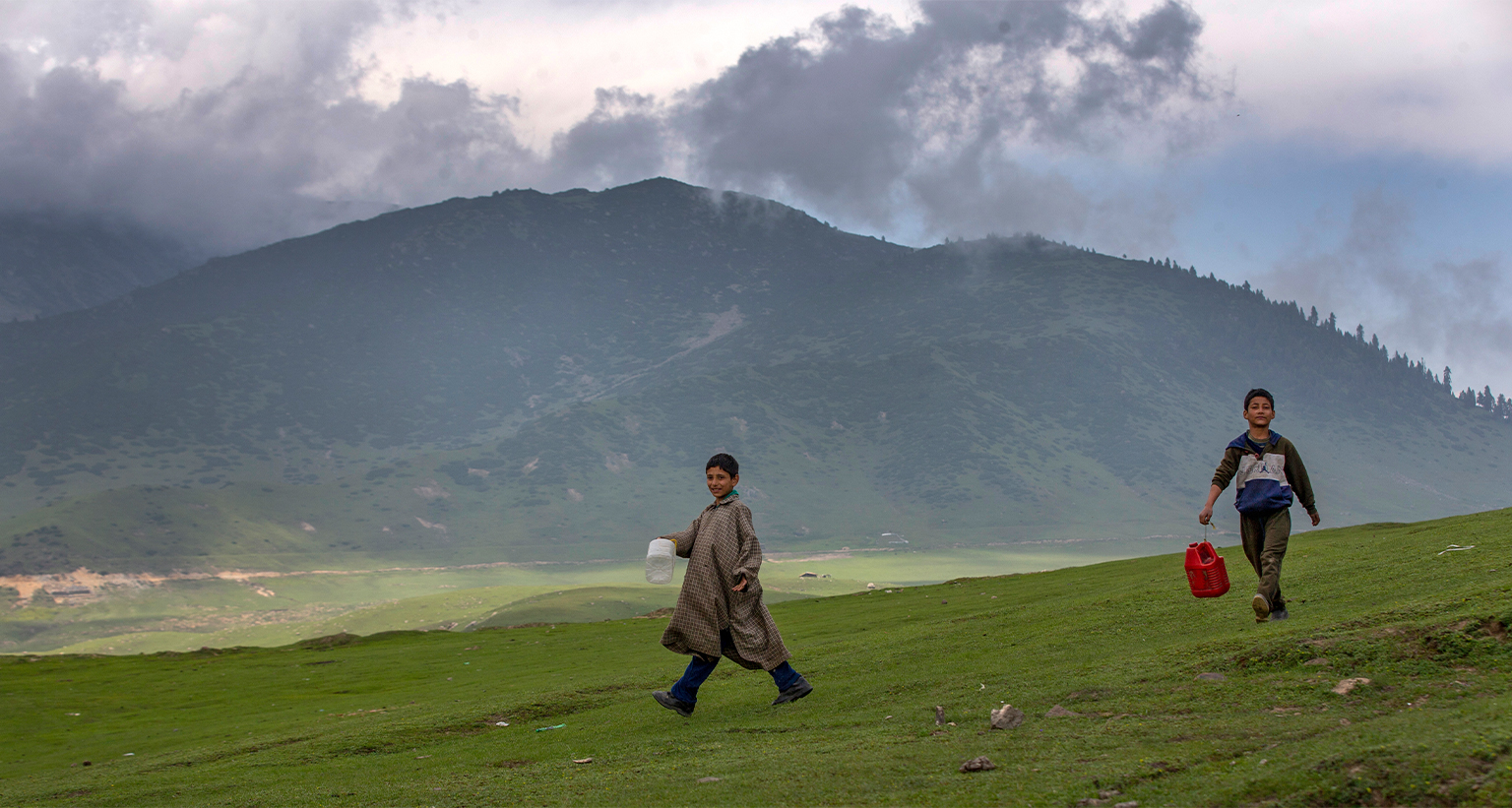 Kashmiri shepherd boys carrying plastic containers walk towards a spring to collect water in Tosamaidan, southwest of Srinagar, 2021. — Image by AP Photo/Dar Yasin.