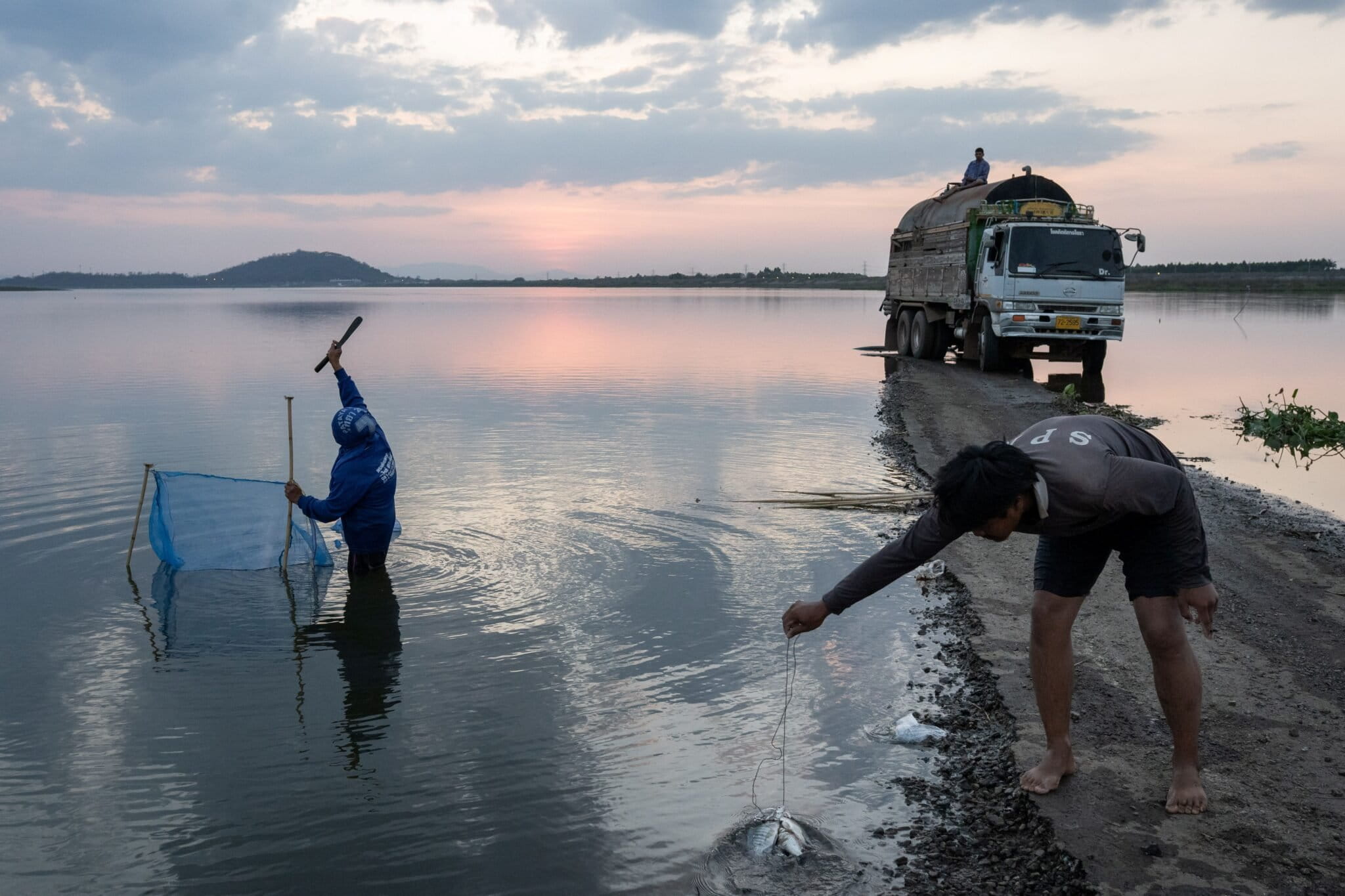 People catch fish in front of a truck pumping water from the Khlong Luang reservoir in Chonburi province, Thailand. Photo by Andy Ball/Mongabay.