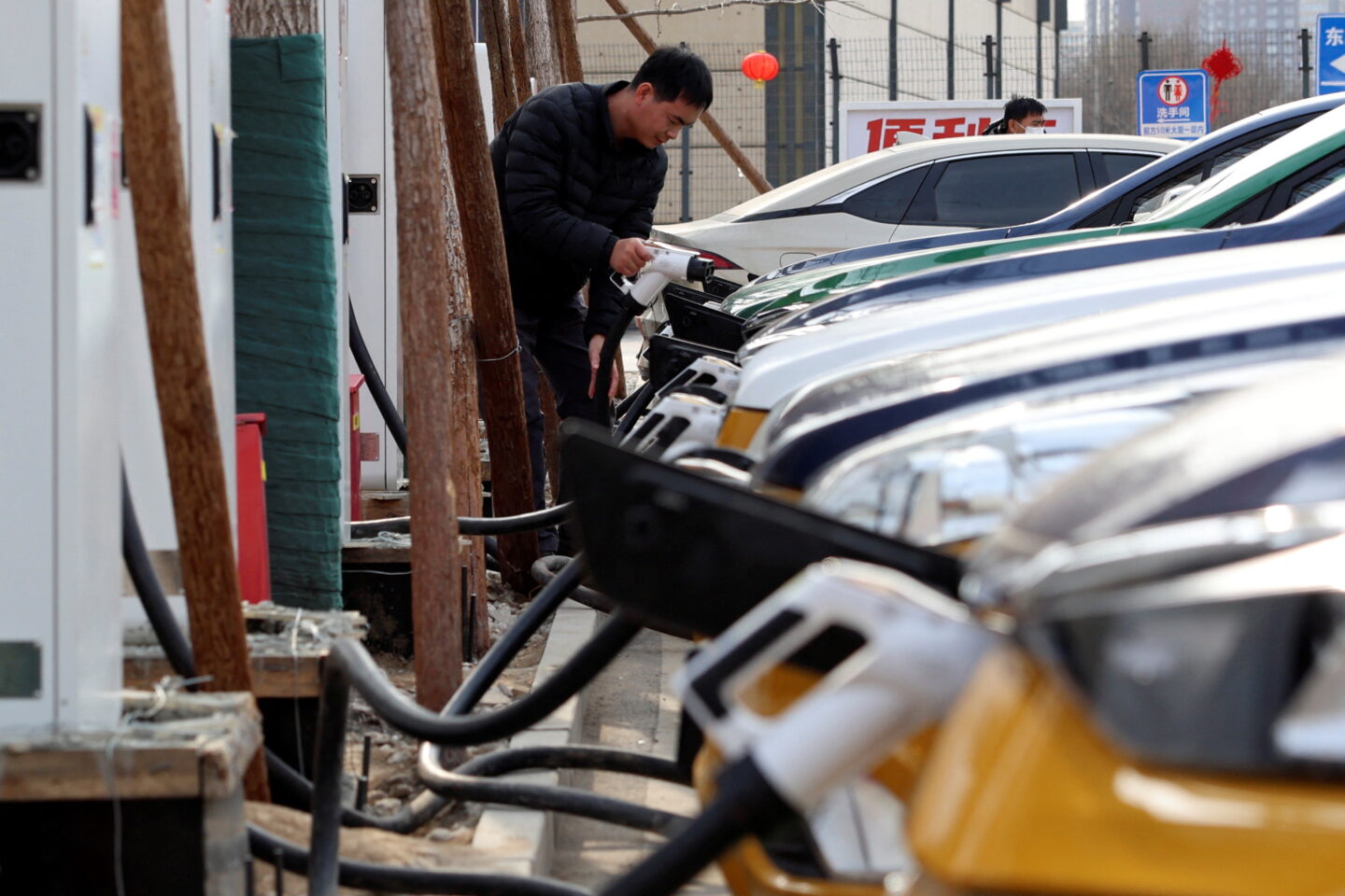 A man holds a charging plug to charge a car at a Smart Charge electric vehicle (EV) charging station in Beijing, China February 2, 2024. REUTERS/Florence Lo