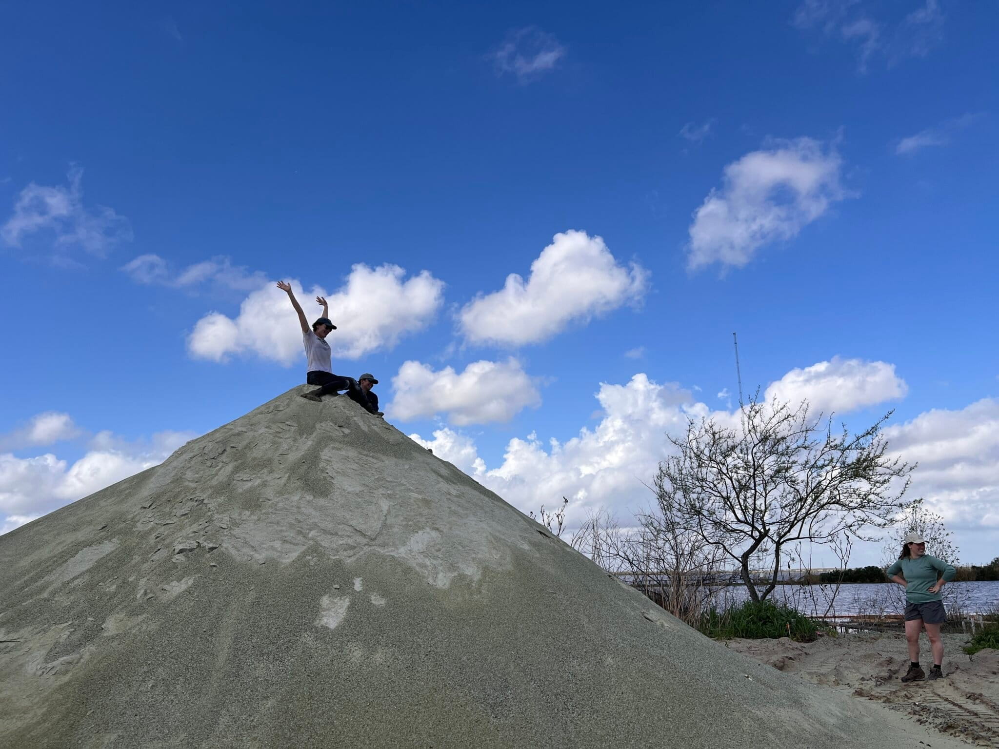 Image by Liz Kimbrough/Mongabay. A volunteer perched atop a pile of recycled glass sand at the Glass Half Full facility. Image by Liz Kimbrough/Mongabay.