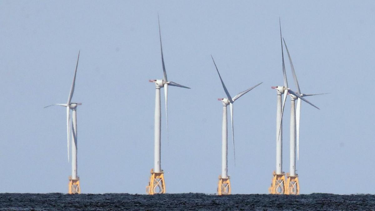 Five wind turbines mounted on yellow metal structures embedded into the sea bed at the Block Island Wind Farm off the coast of Block Island, RI.
