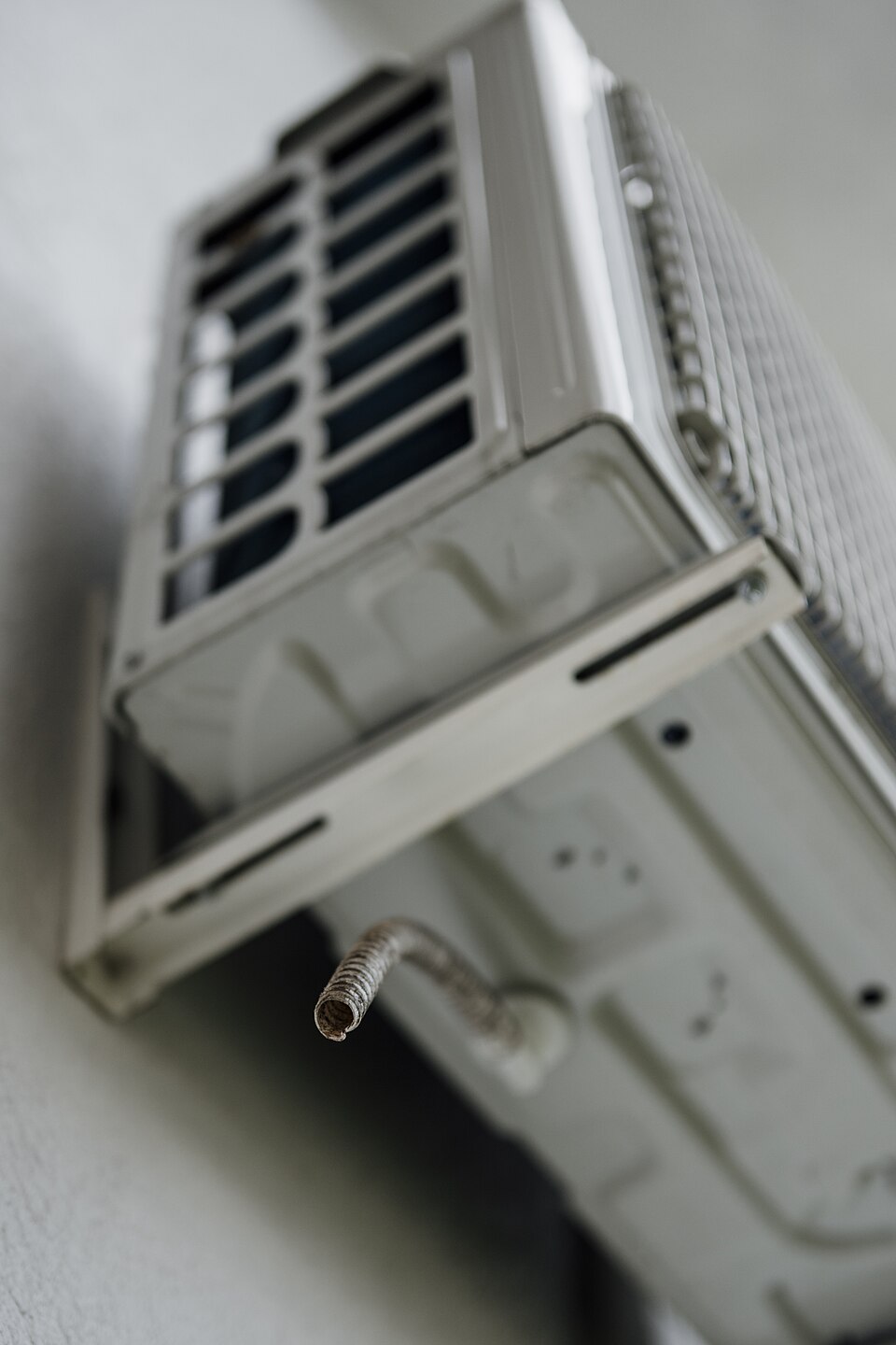 Air conditioning unit mounted on a wall with cooling pipe visible in a residential setting.jpg