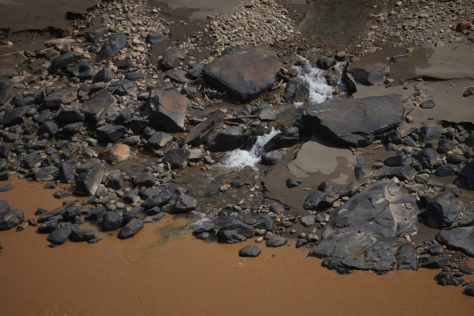 Image by Javier Mamani. A stream in the Retama area flows into the polluted waters of the Kaka River. — Image by Javier Mamani.