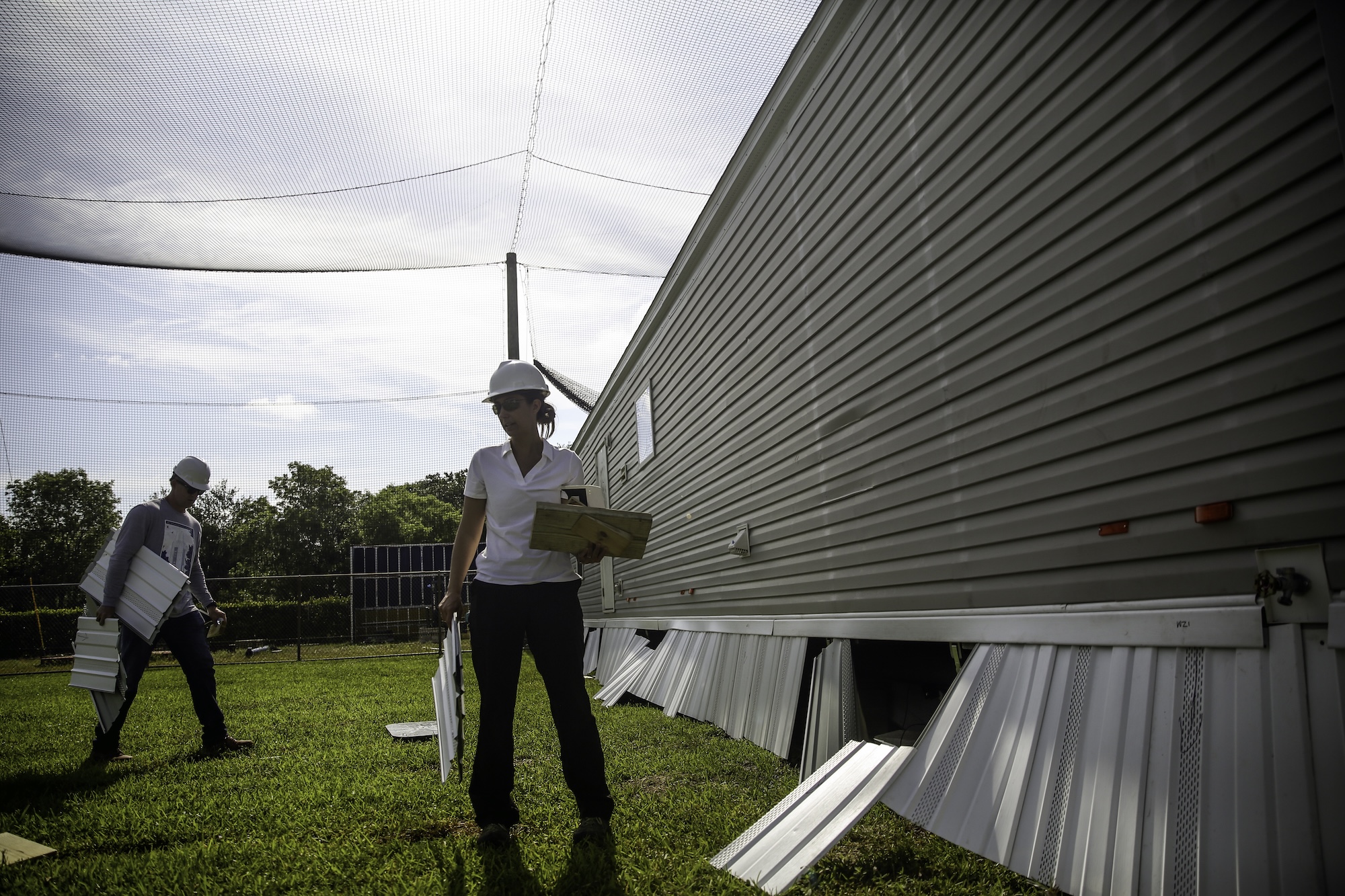 A woman stands near a manufactured home in a testing field for wind