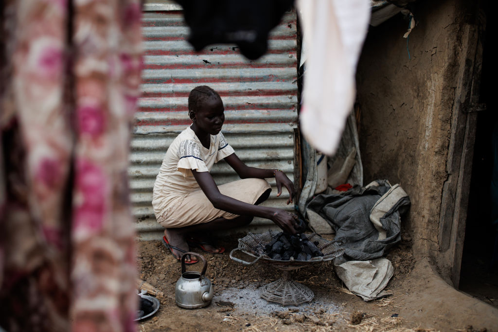 A young girl prepares a charcoal cooking stove at her home in an Internally Displaced Persons (IDP) camp on November 29, 2023 in Bentiu, South Sudan. (Photo by Luke Dray/Getty Images)